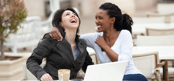 Two women sitting having a coffee and laughing