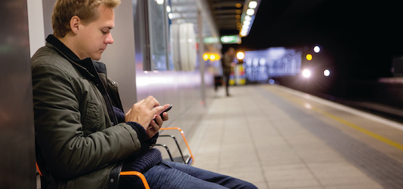 Man on railway platform looking at smartphone
